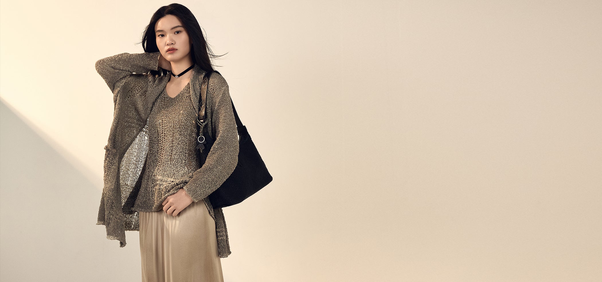 Woman holding a black handbag against a beige background